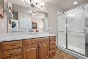 Bathroom with ceiling fan, washer / clothes dryer, a stall shower, and vanity