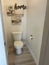 Bathroom featuring baseboards, toilet, and wood finished floors