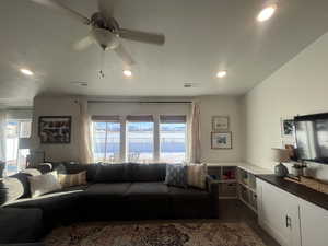 Living room featuring dark colored carpet, plenty of natural light, visible vents, and a ceiling fan