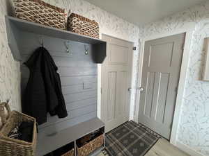 Mudroom featuring light wood-style flooring and wallpapered walls