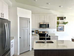 Kitchen featuring lofted ceiling, light wood-style flooring, stainless steel appliances, open shelves, and modern cabinets