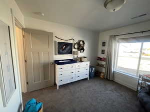 Bedroom featuring dark colored carpet and visible vents