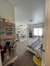 Carpeted bedroom with baseboards and a textured ceiling