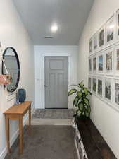 Interior space with visible vents, dark carpet, and baseboards