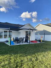 Rear view of property with fence, a lawn, and a patio