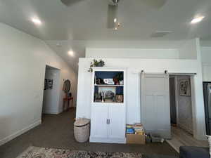 Interior space featuring lofted ceiling, a barn door, visible vents, and baseboards