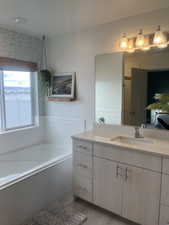 Bathroom featuring wood finished floors, vanity, and a bath