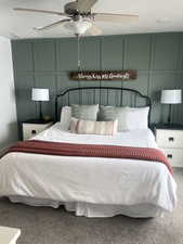 Bedroom with a ceiling fan, carpet flooring, a decorative wall, and a textured ceiling