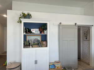 Room details with a barn door, wood finished floors, and baseboards