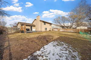 Back of house featuring a chimney, a fenced backyard, a yard, and a deck