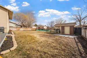 View of yard with a shed, a fenced backyard, and an outbuilding