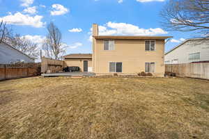 Rear view of property featuring a fenced backyard, a chimney, a wooden deck, and a lawn