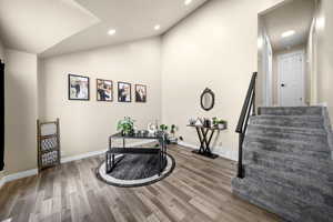 Exercise room with vaulted ceiling, recessed lighting, wood finished floors, and baseboards