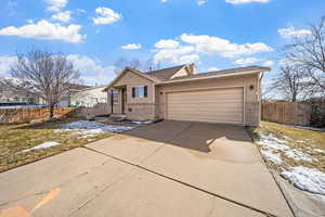 Ranch-style house featuring a garage, concrete driveway, a chimney, fence, and brick siding