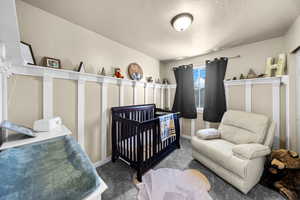 Carpeted bedroom featuring a textured ceiling and baseboards