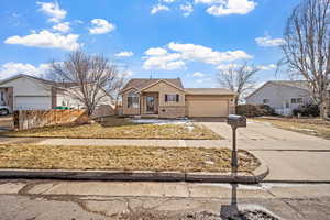 View of front of house with driveway, an attached garage, fence, and brick siding