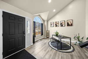 Foyer entrance with lofted ceiling, light wood-style flooring, baseboards, and recessed lighting