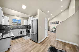 Kitchen featuring appliances with stainless steel finishes, light wood-type flooring, white cabinetry, and a sink