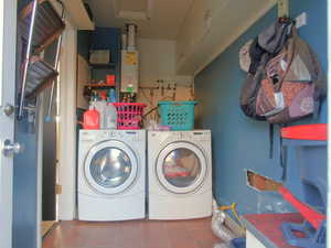 Laundry area featuring washing machine and dryer, laundry area, tile patterned flooring, and tankless water heater