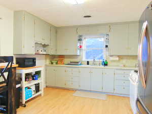 Kitchen with visible vents, black microwave, light countertops, and a sink