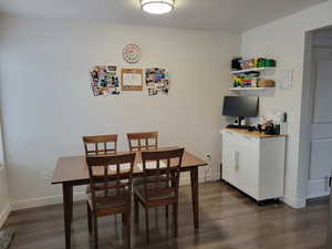 Dining space with dark wood-style floors and baseboards