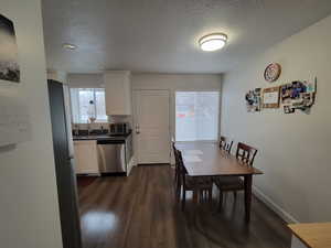 Dining area featuring dark wood-style floors, baseboards, and a textured ceiling, and Back door.