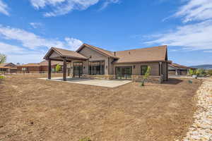 Rear view of house featuring stone siding, french doors, a shingled roof, and a patio