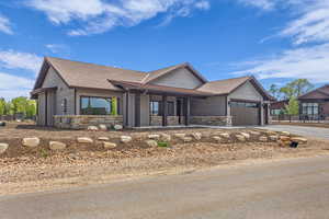 View of front of house with stone siding, concrete driveway, a garage, and a shingled roof