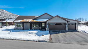 Craftsman-style home with a garage, stone siding, and driveway