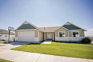 View of front of house with board and batten siding, a front yard, driveway, and a garage