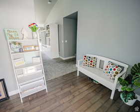 Game room featuring lofted ceiling, dark wood-style floors, and baseboards