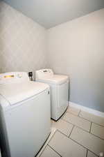 Laundry area featuring laundry area, light tile patterned floors, wallpapered walls, baseboards, and washer and dryer