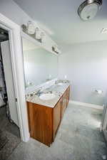 Full bathroom with double vanity, baseboards, visible vents, and a sink