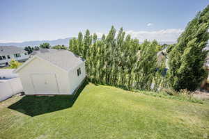 Exterior space featuring fence, a storage unit, a mountain view, and an outbuilding