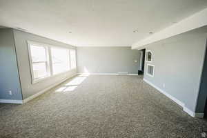 Unfurnished room featuring baseboards, carpet, visible vents, and a textured ceiling