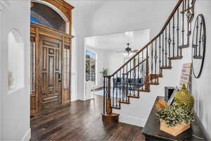 Foyer featuring arched walkways, dark wood-style flooring, a ceiling fan, baseboards, and stairway