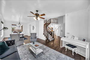 Living area with arched walkways, dark wood-style flooring, baseboards, and stairs