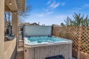 View of patio featuring fence and a hot tub