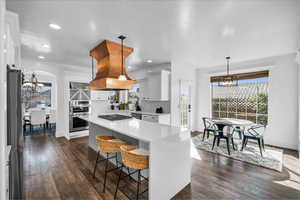 Kitchen featuring a kitchen island, white cabinetry, hanging light fixtures, light countertops, and an inviting chandelier