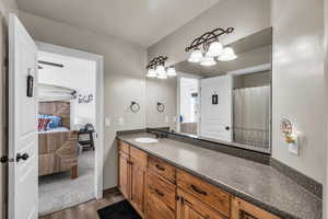 Ensuite bathroom with vanity, ensuite bath, and wood finished floors