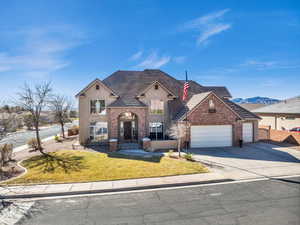 View of front facade with an attached garage, a mountain view, brick siding, driveway, and stucco siding