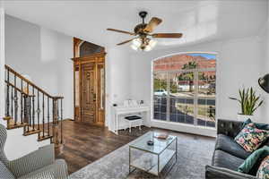 Living area with stairs, dark wood finished floors, and a ceiling fan