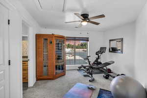 Exercise area with carpet flooring, attic access, and baseboards