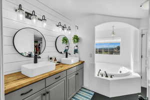 Full bathroom featuring double vanity, a garden tub, tile patterned flooring, and a sink