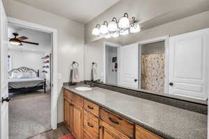 Bathroom featuring ensuite bathroom, wood finished floors, vanity, baseboards, and a ceiling fan