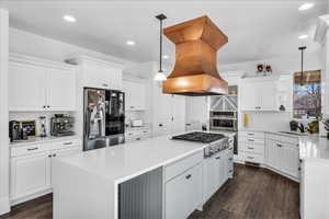 Kitchen with appliances with stainless steel finishes, white cabinets, hanging light fixtures, and open shelves