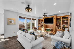 Living room with dark wood-type flooring, recessed lighting, and baseboards