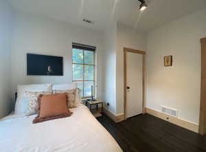 Bedroom with dark wood finished floors, visible vents, and baseboards