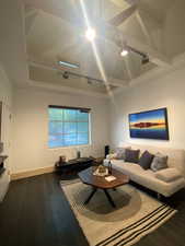 Living room featuring dark wood-style flooring, a raised ceiling, and baseboards