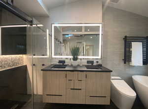 Bathroom with lofted ceiling, a sink, tile walls, and double vanity